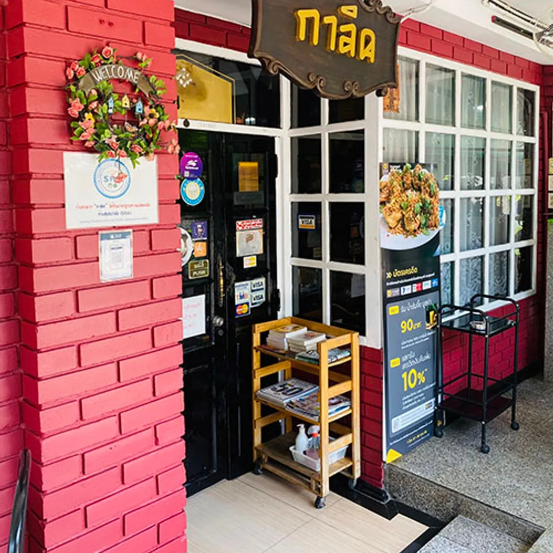 The entrance to Garlic: a red brick wall with white window frames and the carved wooden sign above the door.