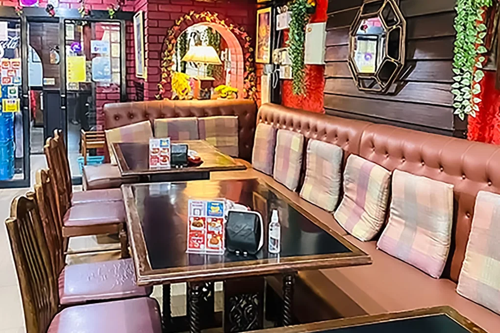 Inside: buttoned banquettes, a gilt mirror and garlands against dark timber.